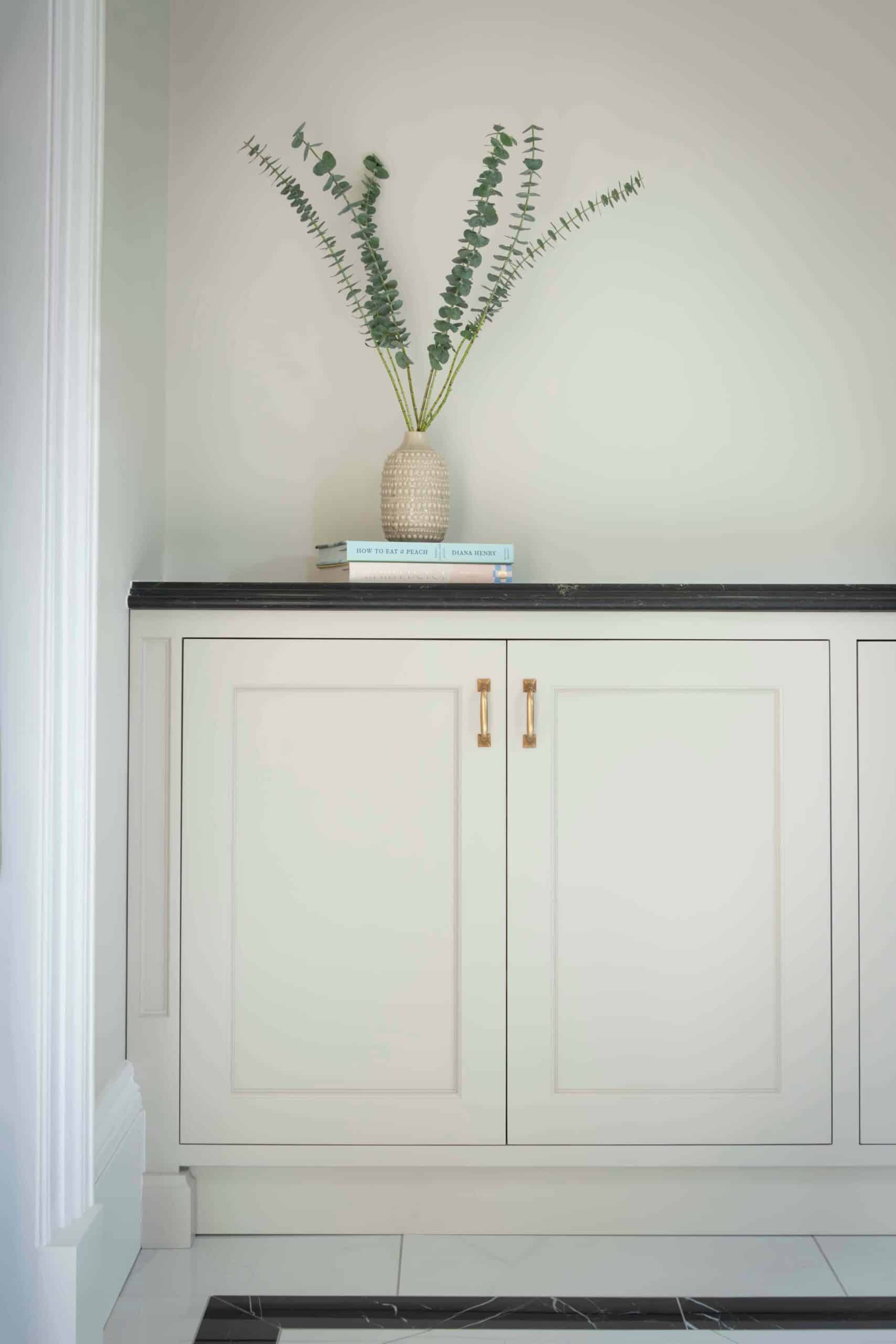 White cupboard with white vase and books on top