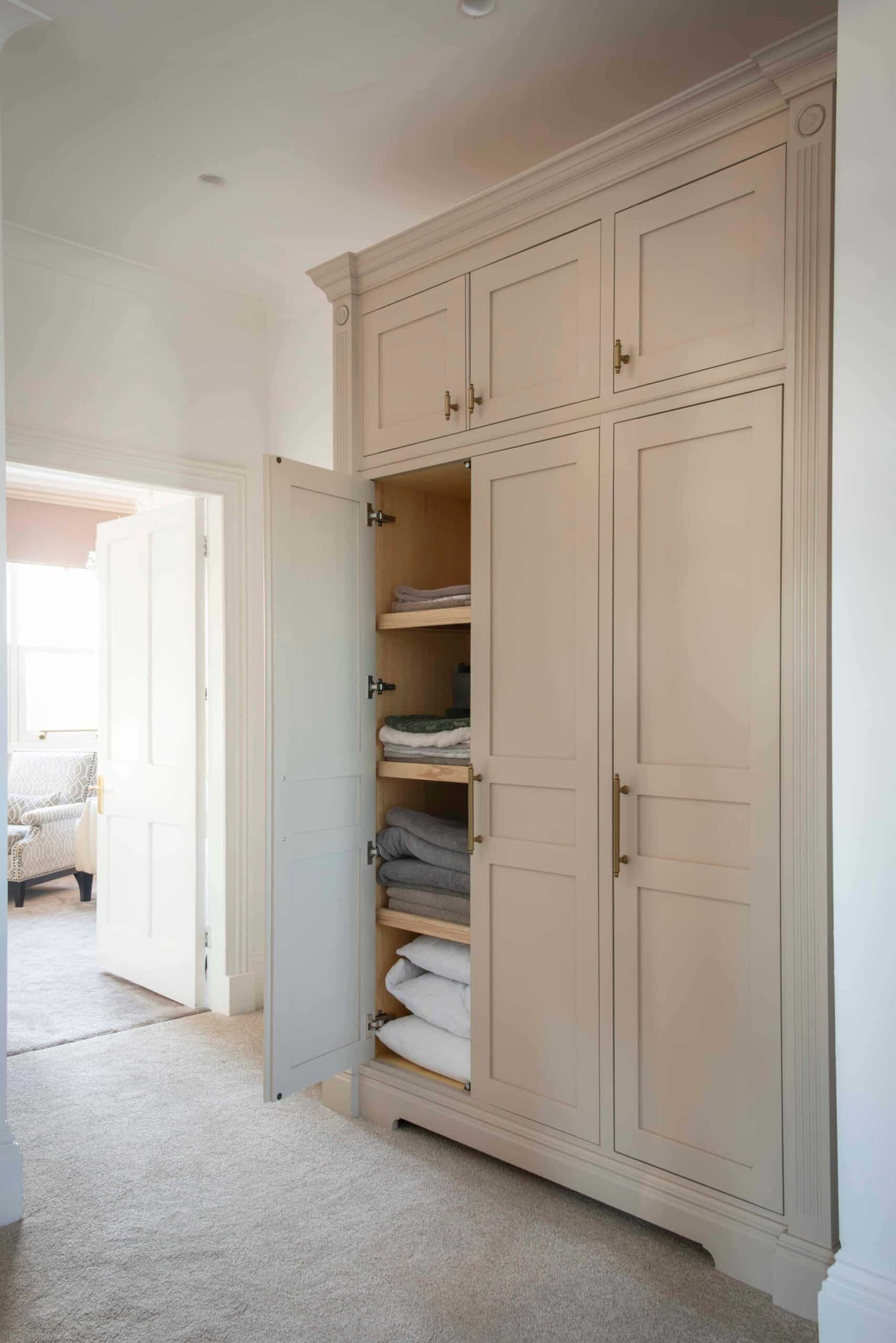 White wardrobe displayed with open door with period features as part of a collection of bespoke furniture for a Victorian House
